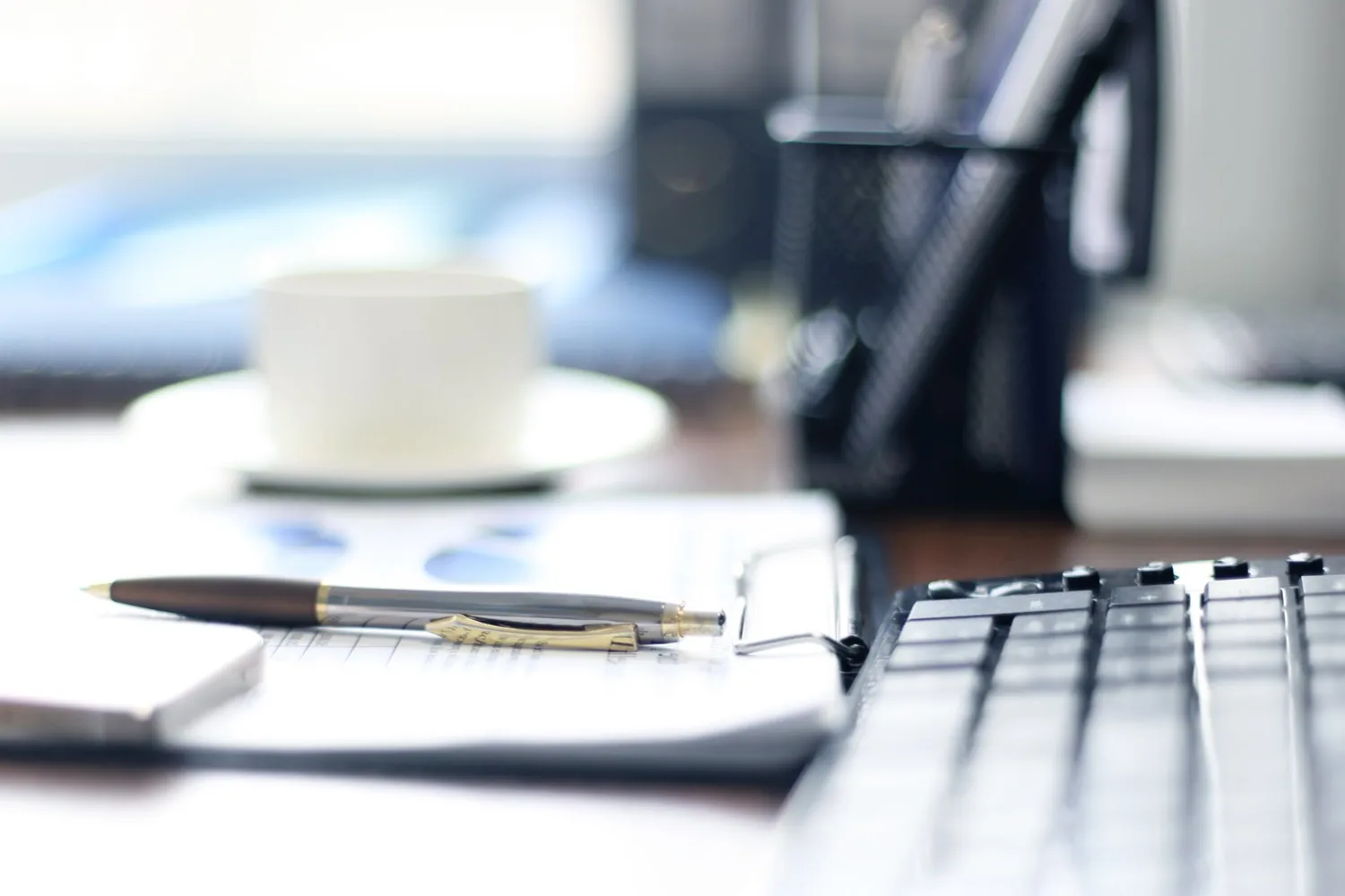 A desk with a laptop, notepad and coffee, ready for an interview
